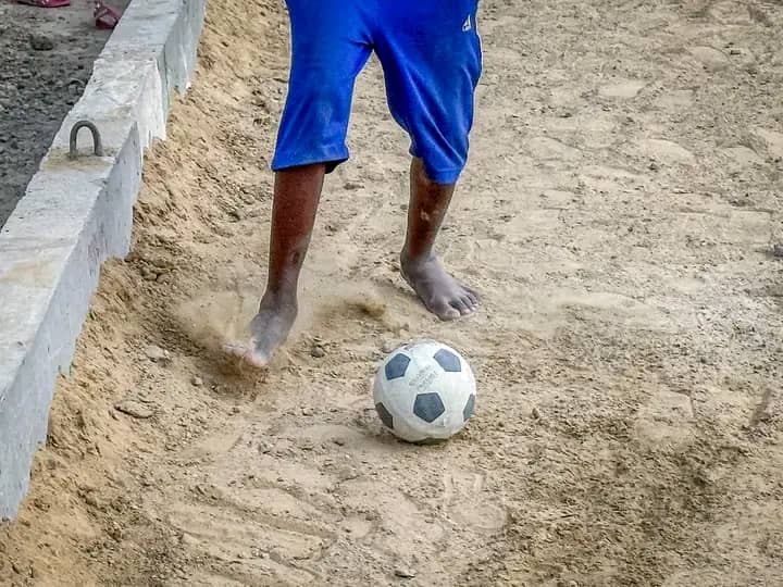 Football : sur les voies brutes, les enfants tracent leur route, pratiquant le football pieds nus.